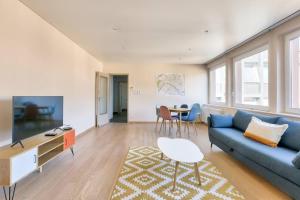 een woonkamer met een blauwe bank en een tafel bij Appartement spacieux au cœur de Strasbourg in Straatsburg