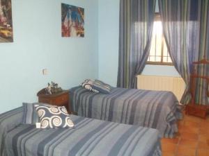 a bedroom with two beds and a window at Casa Rural El Hollejo in Pulgar