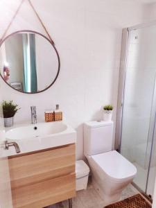bagno con servizi igienici, lavandino e specchio di Exclusivo Apartamento a 500 metros de la Playa a Castelldefels