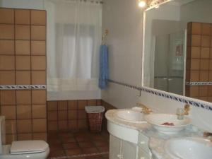 a bathroom with two sinks and a toilet and a mirror at Casa Rural El Hollejo in Pulgar