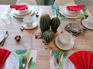 un tavolo in legno con piatti e tazze bianchi e un cactus di Exclusivo Apartamento a 500 metros de la Playa a Castelldefels