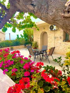 un patio con flores rojas, mesa y sillas en Poseidon Apartments en Kíssamos