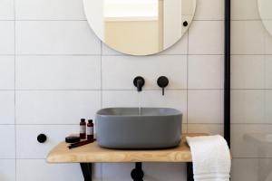 bagno con lavabo a ciotola e specchio di La VIA Rooms and Terrace a Olbia