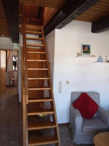 escalera de madera en una habitación con sofá y silla en Ferienwohnung Baade -KEINE MONTEURE-, en Friedrichskoog-Spitz