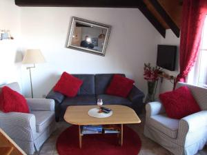 sala de estar con sofá azul y almohadas rojas en Ferienwohnung Baade -KEINE MONTEURE-, en Friedrichskoog-Spitz
