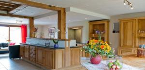 una cocina con armarios de madera y una mesa con flores en Chez ELoy, en Rochehaut