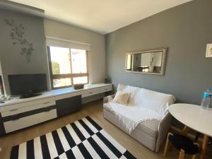 uma sala de estar com um sofá branco e uma televisão em Comfort Flat Pinheiros em Hotel 4,5 estrelas em São Paulo