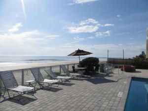 a patio with chairs and an umbrella next to the beach at Lotus Boutique Inn and Suites in Ormond Beach