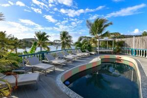 a resort pool with lounge chairs and a view of the ocean at Villa Ordnance in English Harbour Town