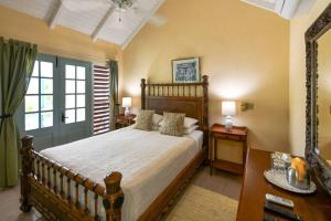 a bedroom with a bed and two tables and a window at Villa Ordnance in English Harbour Town