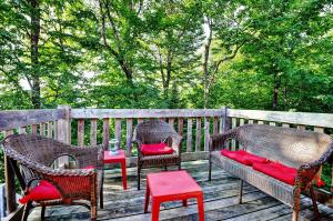 a deck with chairs and a table with red pillows at Chalets Alpins- 10 Chemin des Montagnards in Stoneham