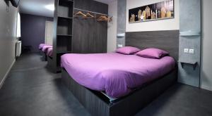 ein Schlafzimmer mit einem großen Bett mit lila Bettwäsche und Kissen in der Unterkunft Hôtel La Tente Verte in Loon-Plage