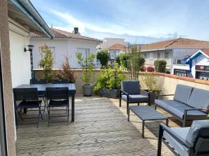 eine Terrasse mit Tisch und Stühlen auf einem Deck in der Unterkunft Appartement Côté Bassin in Andernos-les-Bains