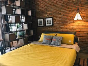 a bedroom with a yellow bed with a brick wall at Sweetheart in Saigon in Ho Chi Minh City