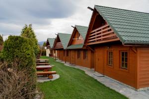wiersz drewnianych budynków z ławkami w rzędzie w obiekcie Domki nad jeziorem-Wodnik w mieście Zarzecze
