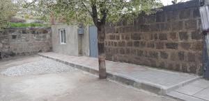un albero seduto accanto a un muro di mattoni con una porta di Hakobyan's Home a Gyumri