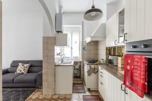 uma pequena cozinha com armários brancos e um sofá azul em Mestre Altamarea Apartment em Mestre