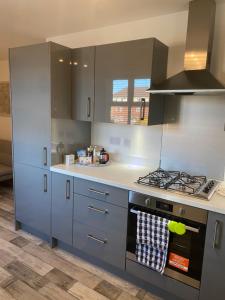 een keuken met grijze kasten en een fornuis met oven bij Peterborough City Center One Bed apartment With Free Private Parking in Peterborough