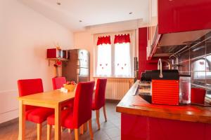 uma cozinha com uma mesa de madeira e cadeiras vermelhas em Malpensa Garden em Case Nuove