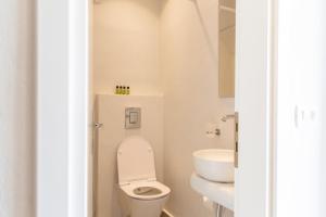 a white bathroom with a toilet and a sink at Asimina Hotel in Fira