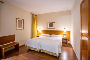 a bedroom with a large white bed and two tables at YIT Conquista de Toledo in Toledo