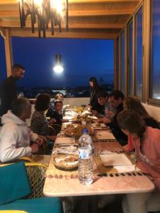 Un groupe de personnes assises autour d'une table et mangeant de la nourriture dans l'établissement Atlantic Hostel, à Essaouira