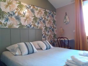 een slaapkamer met een bed met 2 kussens erop bij contact hôtel Le Temps Perdu in Le Bois de Cise