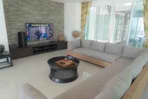 Nirvana Hua Hin Pool Villa في فيتشابوري: غرفة معيشة مع أريكة وتلفزيون