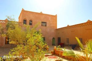a large brick building with trees in front of it at Hotel Riad Le Petit Prince in Merzouga