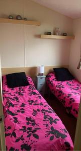 a bedroom with two beds and a pink blanket at Whitley bay caravan retreat in Whitley Bay