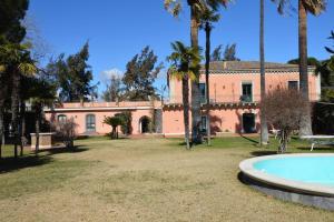 an old house with a swimming pool and palm trees at La Casetta Rosa alloggio indipendente, four beds in Mascalucia