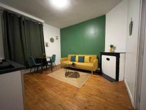 ein Wohnzimmer mit einem gelben Sofa und einem Tisch in der Unterkunft Peaceful Apparts Saint-Quentin in Saint-Quentin