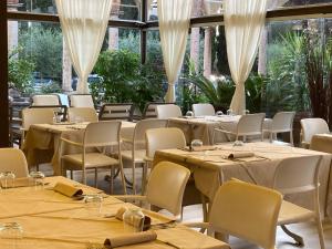 uma sala de jantar com mesas, cadeiras e janelas em Locanda Al Santuario em Peschiera del Garda