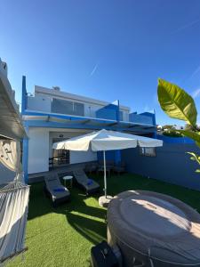 une terrasse avec un parasol, des chaises et une maison dans l'établissement Royal Luxury Studios, à Archangelos