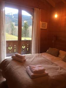 um quarto com uma cama com toalhas e uma janela em Chalet Pierre, Les Gets em Les Gets