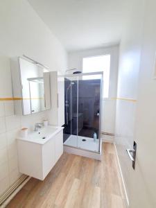 een witte badkamer met een douche en een wastafel bij Le Carillon - hypercentre - WIFI in Douai