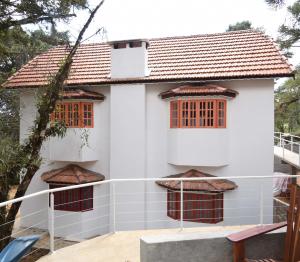 une maison blanche avec des fenêtres rouges sur un balcon dans l'établissement Pousada Vila Suiça - Monte Verde, à Monte Verde