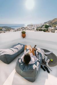 una donna sdraiata su un letto a sacco di fagioli su un balcone di ARTE LINDOS SUITES a Líndos