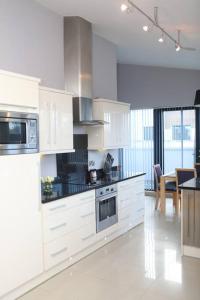 a kitchen with white cabinets and a table in it at Luxury Three Bedroom Apartment Foxford County Mayo in Foxford