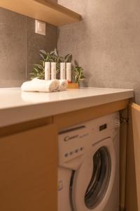 a laundry room with a washing machine under a counter at Aeson Premium Living in Volos