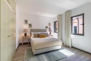 ein weißes Schlafzimmer mit einem Bett und einem Fenster in der Unterkunft Fort Bay Suite Apartments in Machico