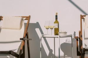 a bottle of wine and two glasses on a table at ARTE LINDOS SUITES in Lindos