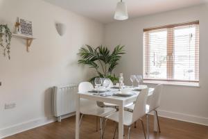 uma sala de jantar branca com uma mesa e cadeiras brancas em Bright, Modern, Fully Furnished Apartment - 2 FREE PARKING Spaces - 8 min LGW Airport em Crawley