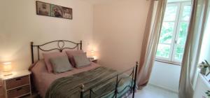 a bedroom with a bed with pink pillows and a window at T3 avec sa terrasse au cœur du village médiéval in Sauzet