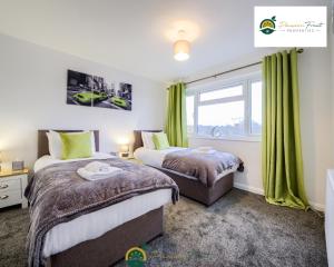 Duas camas num quarto com cortinas verdes e uma janela. em LOW rate SPECIAL DEAL for a 3 Bedroom house with 2 Baths- near Coventry Community Centre and War Memorial Park with Parking and FREE unlimited Wi-fi - ARC em Coventry