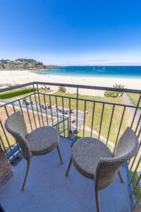 uma varanda com 2 cadeiras e vista para a praia em Logis Hôtel Ker Mor em Perros-Guirec