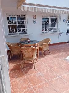een patio met een tafel, stoelen en ramen bij Granada playa! in Maspalomas