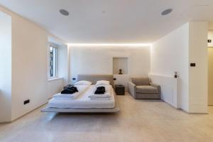 a white bedroom with two beds and a chair at App 203 Palazzo Cavour in Bolzano