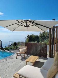 patio con tavolo e ombrellone accanto alla piscina di Casa Lunga à Erbalunga- A deux pas de la plage a Brando