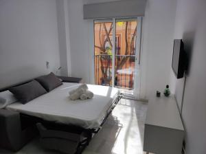 Cama blanca en habitación con ventana en Garu Apartamentos, en Fuengirola